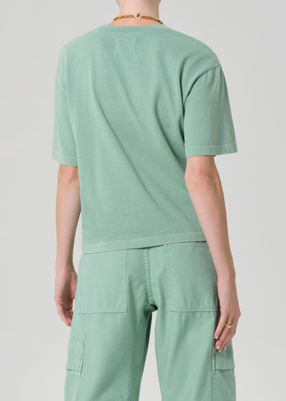 Person wearing a light green t-shirt and cargo pants on a plain background