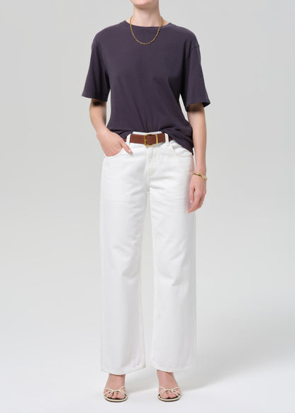 Person wearing a charcoal t-shirt and white pants with a plain background