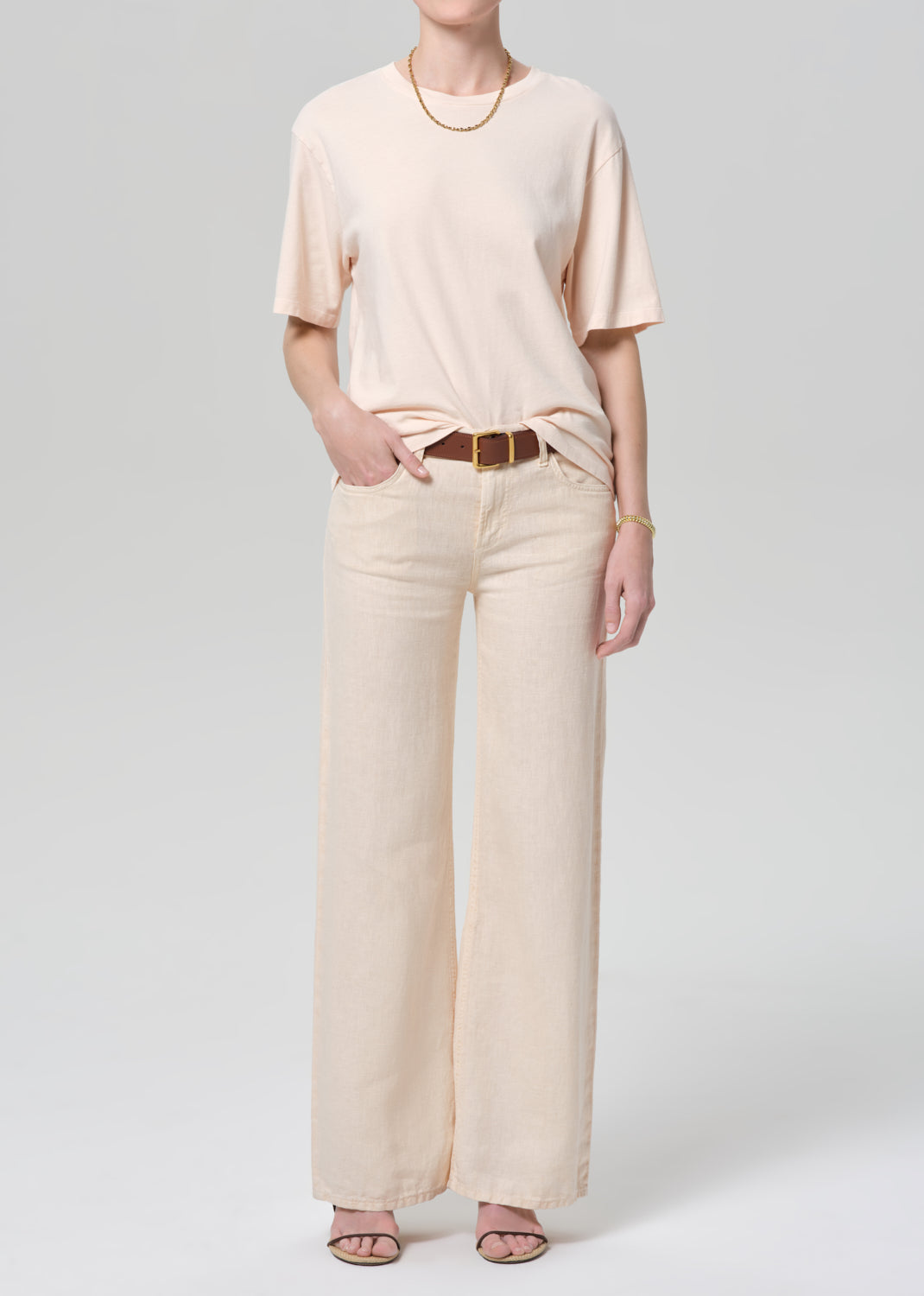 Person wearing a light pink t-shirt and pants on a plain background