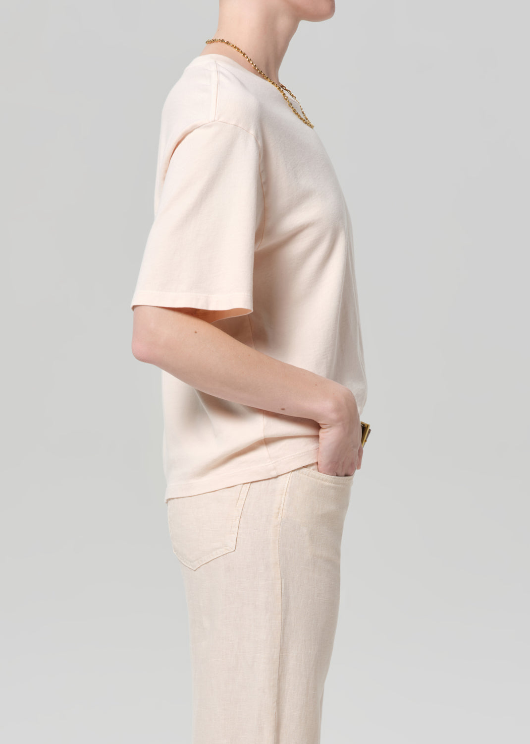 Person wearing a light pink t-shirt and pants on a plain background