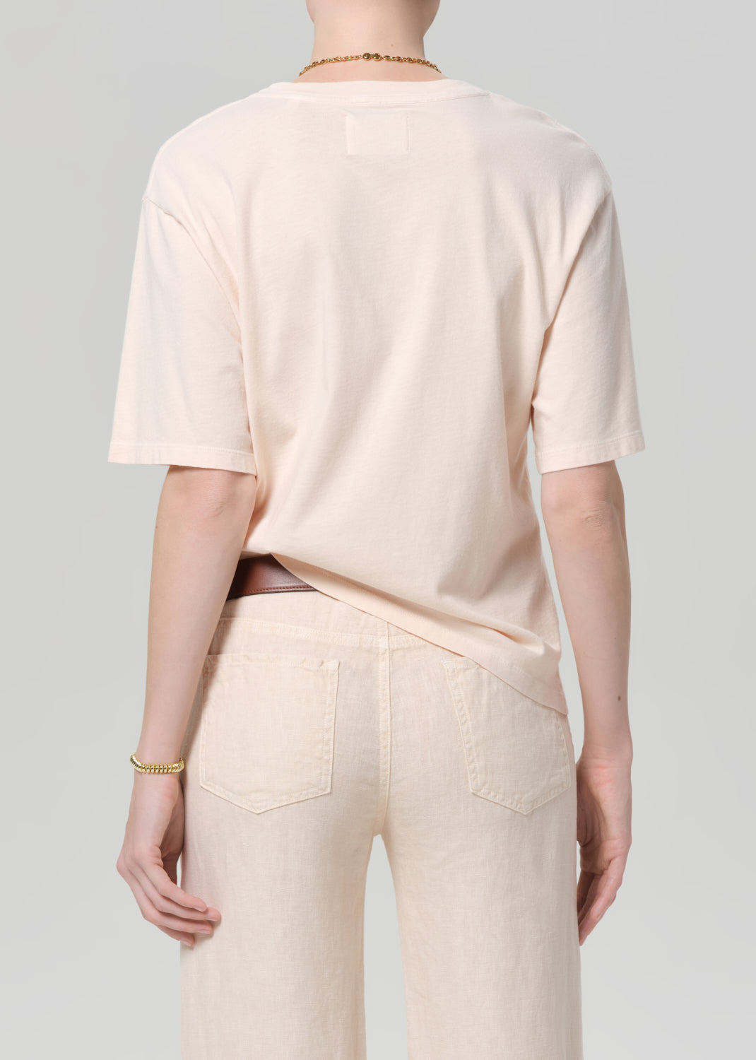 Person wearing a light pink t-shirt and pants on a plain background