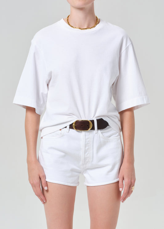 Person wearing a white t-shirt and white shorts with a belt on a plain background