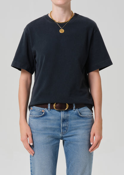 Person wearing a black t-shirt and blue jeans with a plain background