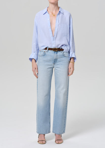 Person wearing a light blue shirt and jeans on a white background