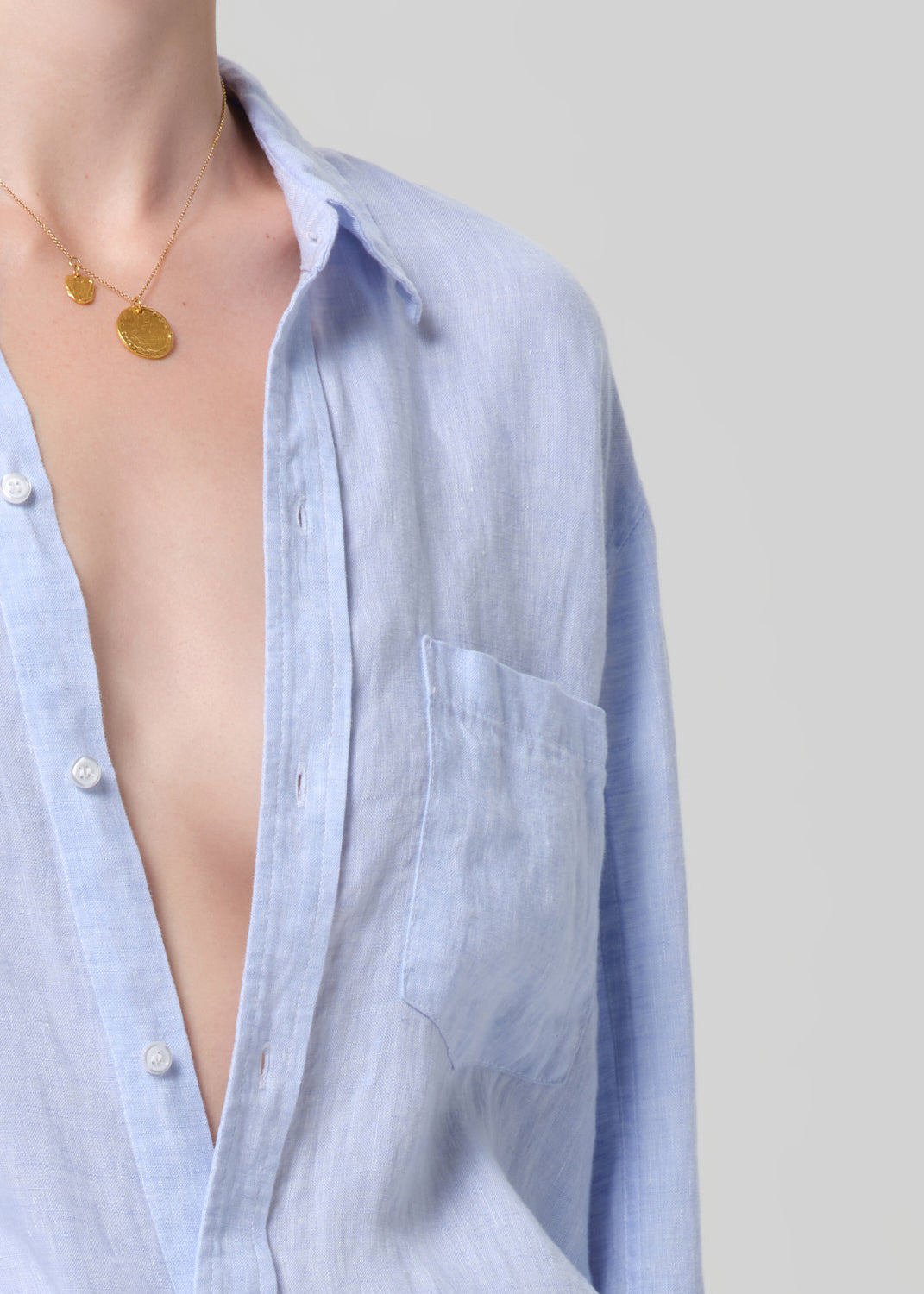 Light blue shirt with a necklace on a neutral background