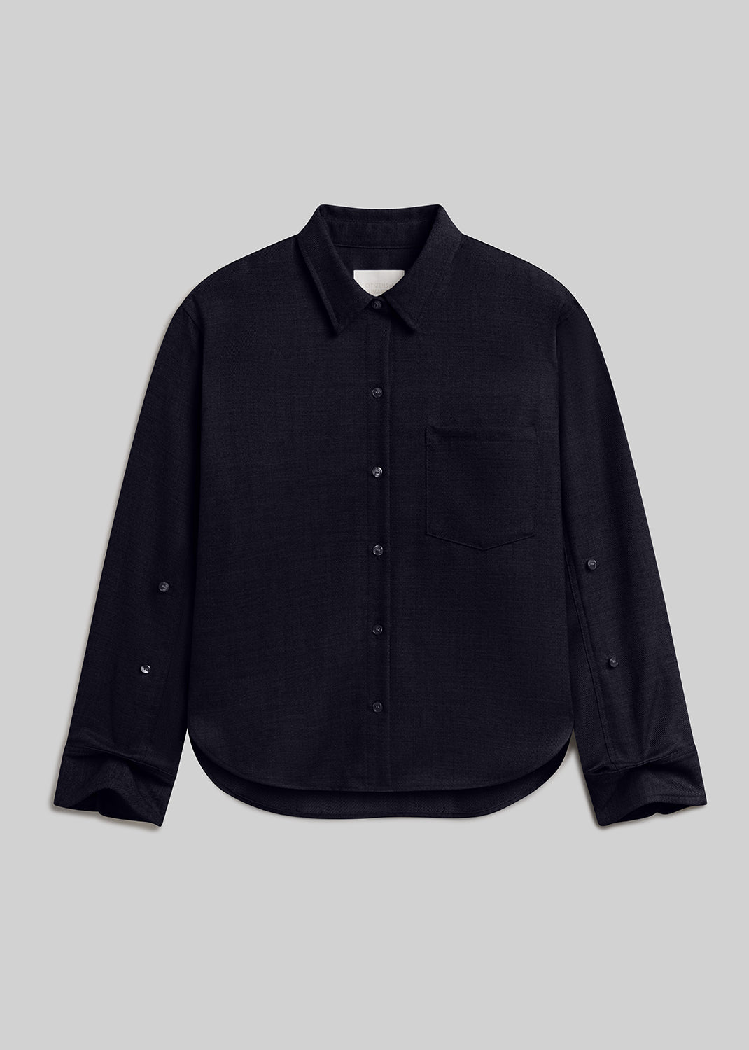 Kayla Shrunken Shirt in dark navy, featuring a pointed collar, front button closure, single chest pocket, long sleeves, and a curved hem, front view on a grey background.
