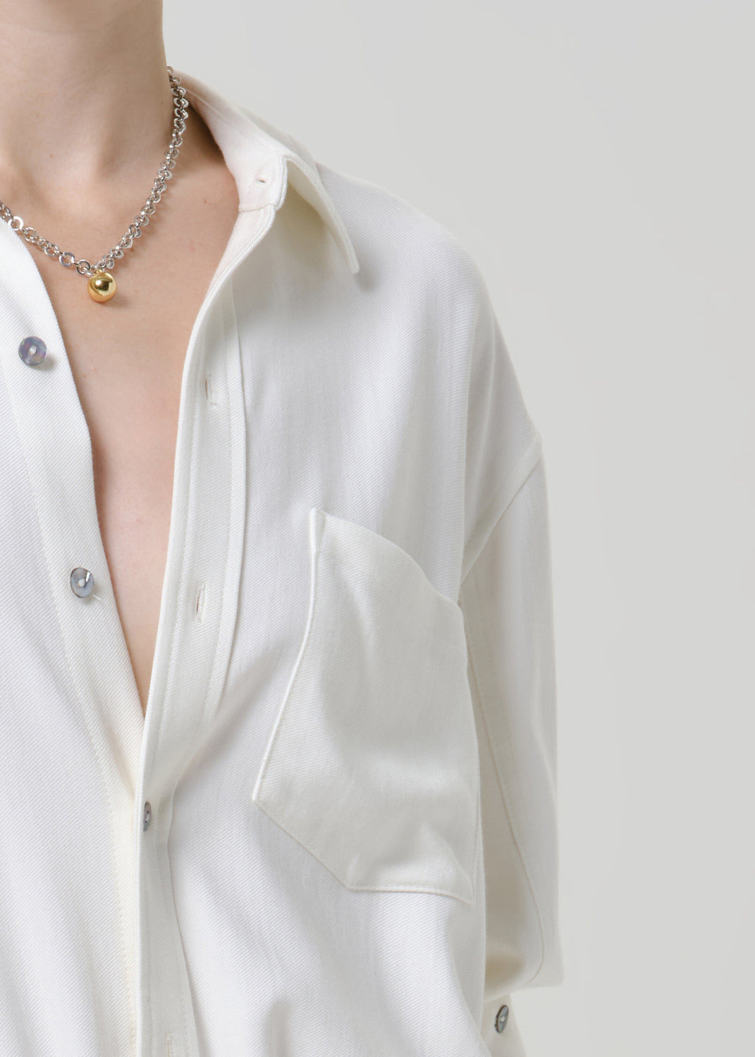 Close-up of a white button-up shirt on a grey background.