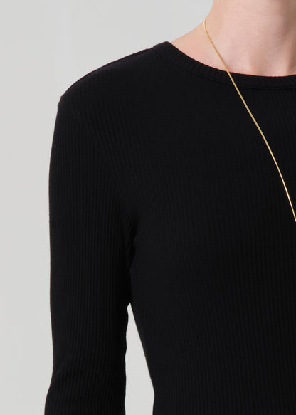 Black long-sleeve top worn by a person on a light gray background