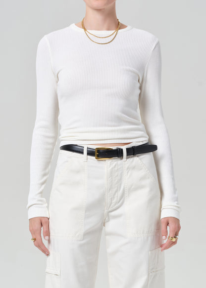 Person wearing a white long-sleeve top and white cargo pants with a black belt on a plain background