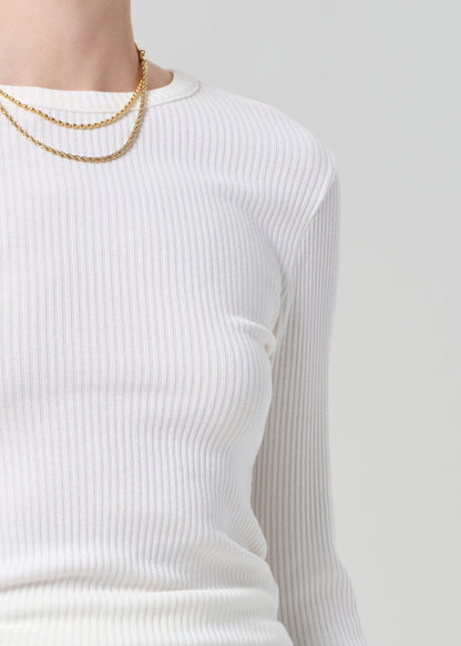 Person wearing a white long-sleeve top on a plain background