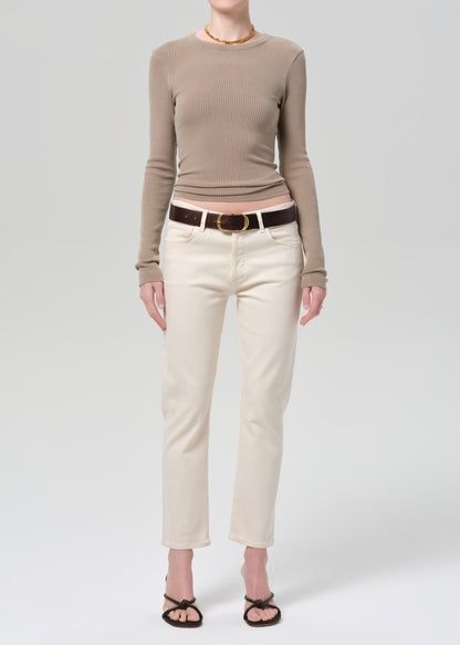 Person wearing a brown ribbed sweater and beige pants on a grey background