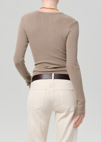 Person wearing a beige ribbed sweater and cream pants on a plain background