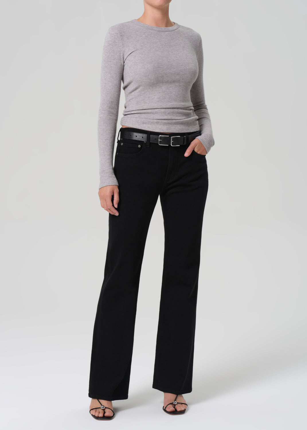 Person wearing a gray sweater and black pants on a white background