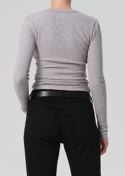 Person wearing a gray sweater and black pants on a light gray background