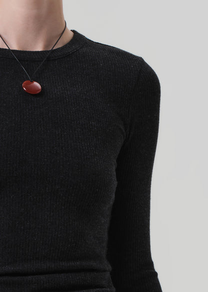 Person wearing a charcoal long-sleeve top and black pants on a light gray background