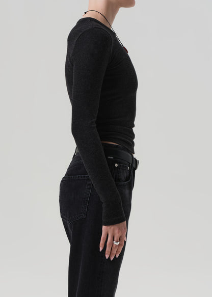 Person wearing a charcoal long-sleeve top and black pants on a light gray background