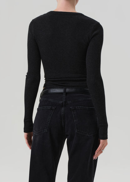 Person wearing a charcoal long-sleeve top and black pants on a light gray background