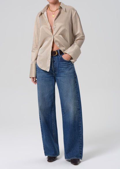 Person wearing a beige shirt and blue jeans on a white background