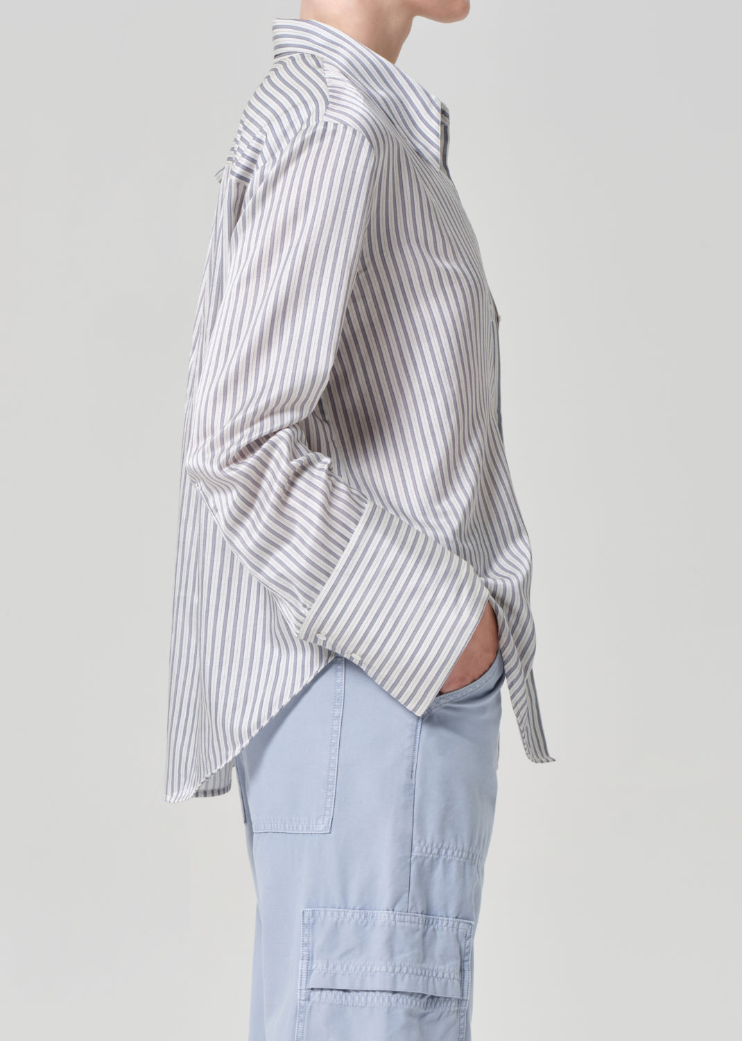 Person wearing a striped shirt and light blue pants on a plain background