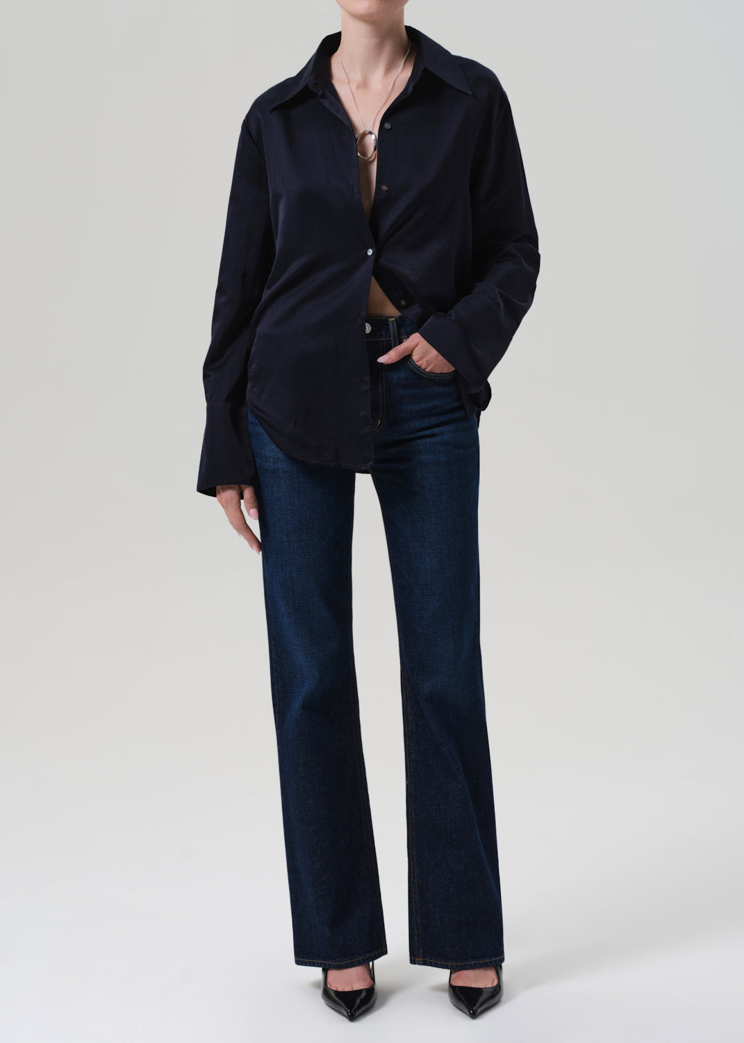 Person wearing a navy shirt and dark blue jeans on a white background