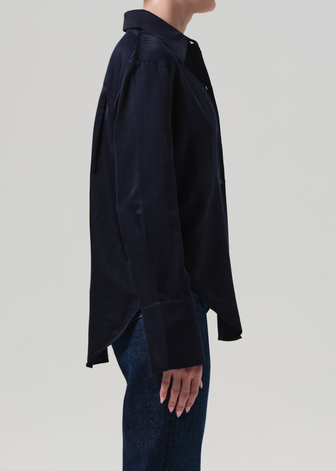 Person wearing a navy shirt and blue jeans on a light gray background