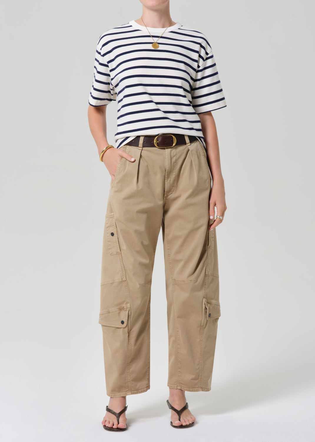 Person wearing a striped shirt and beige cargo pants on a grey background