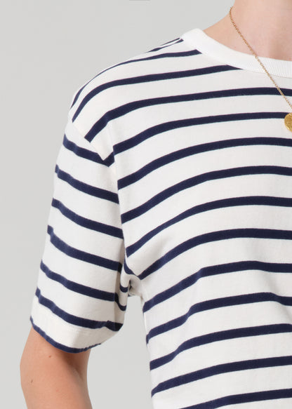 Navy and white striped shirt worn by a person on a gray background