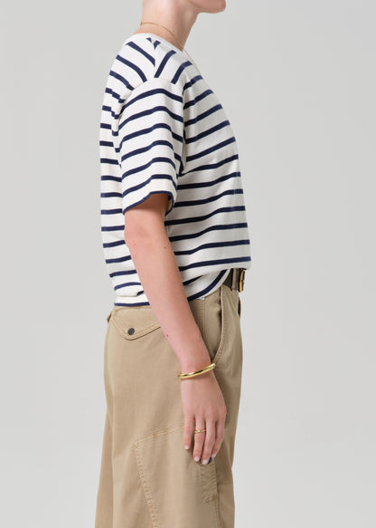 Person wearing a striped shirt and beige pants on a plain background