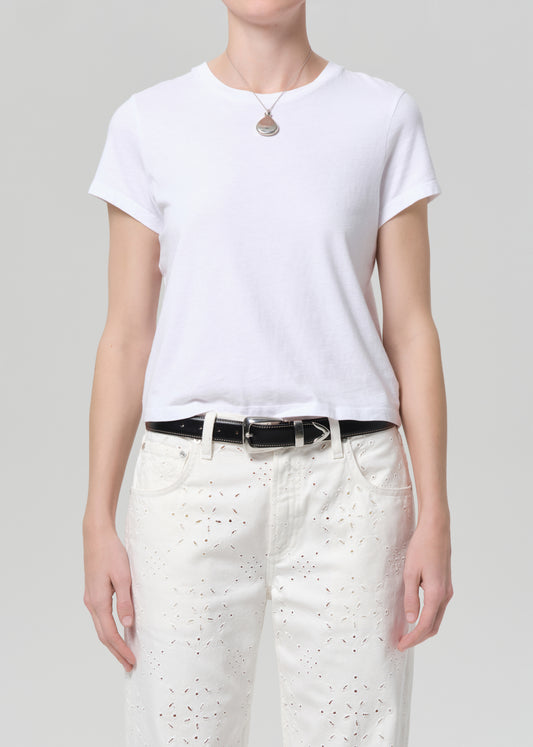 Person wearing a white t-shirt and white pants with a belt on a plain background