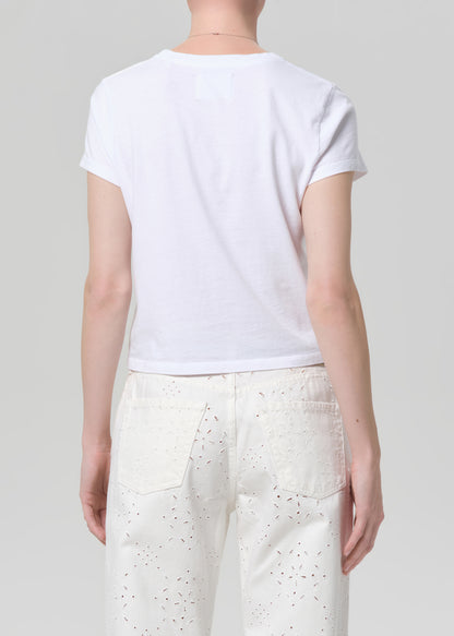 Person wearing a plain white t-shirt and white pants on a light gray background