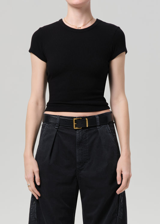 Person wearing a black ribbed tee and black cargo pants on a light gray background