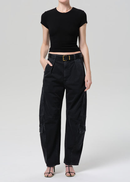 Person wearing a black ribbed tee and black cargo pants on a light gray background