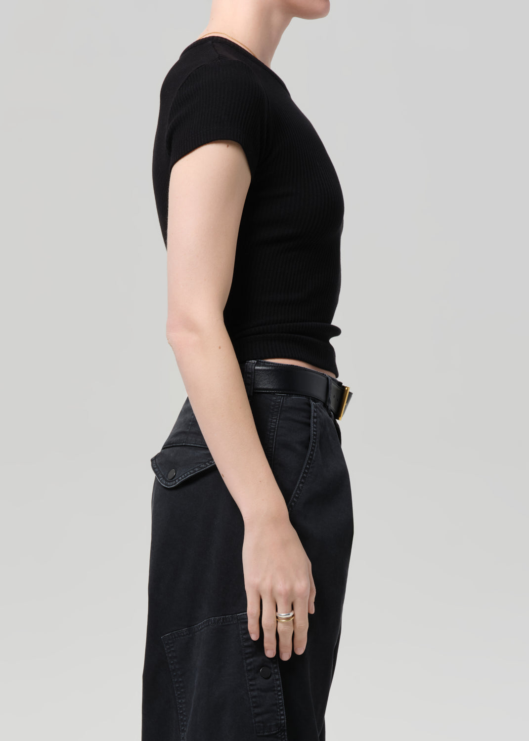 Person wearing a black ribbed tee and black cargo pants on a light gray background