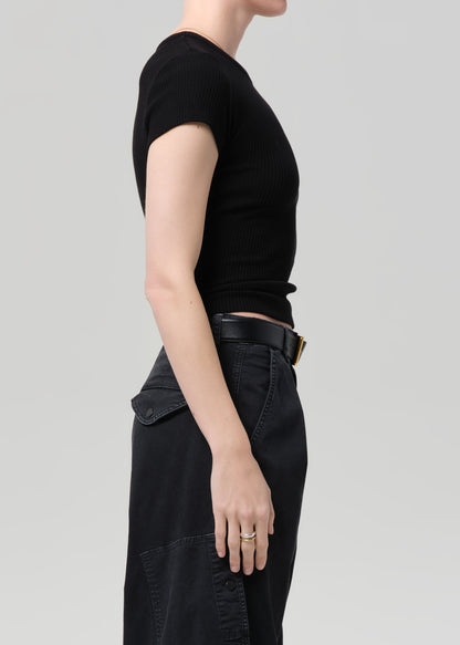 Person wearing a black ribbed tee and black cargo pants on a light gray background