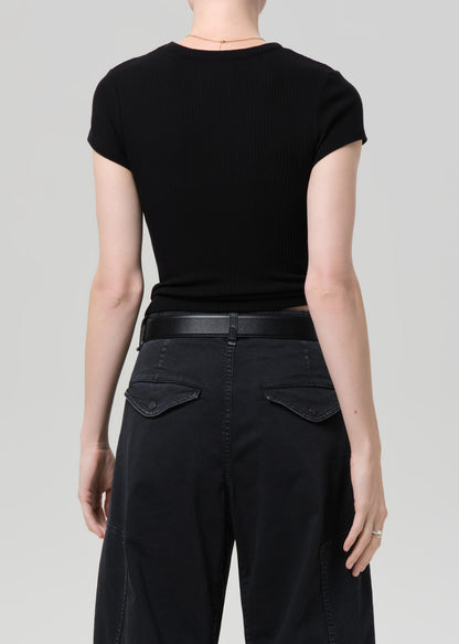 Person wearing a black ribbed tee and black cargo pants on a light gray background