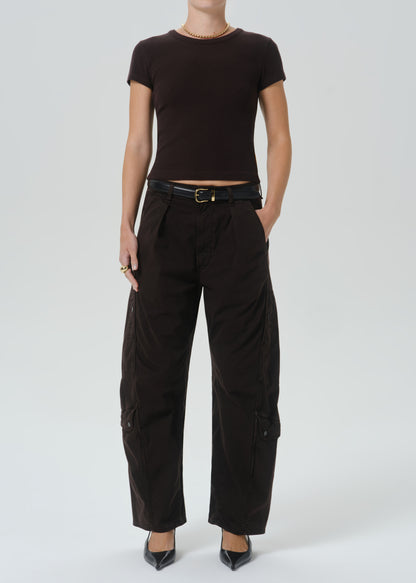 A model wearing a dark brown short-sleeve crop top and black wide-leg cargo pants with a black belt, standing against a grey background.