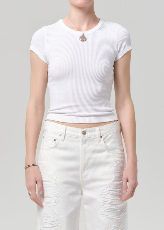 Person wearing a white ribbed crop top and white pants on a gray background