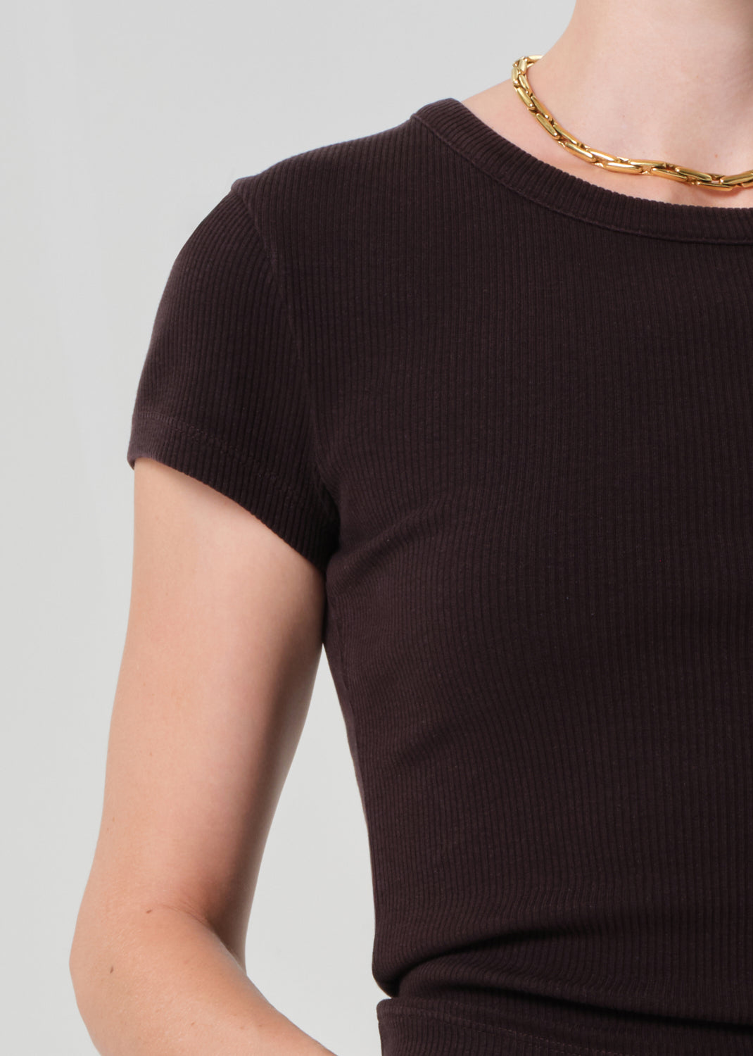 Brown ribbed t-shirt worn by a person on a plain background