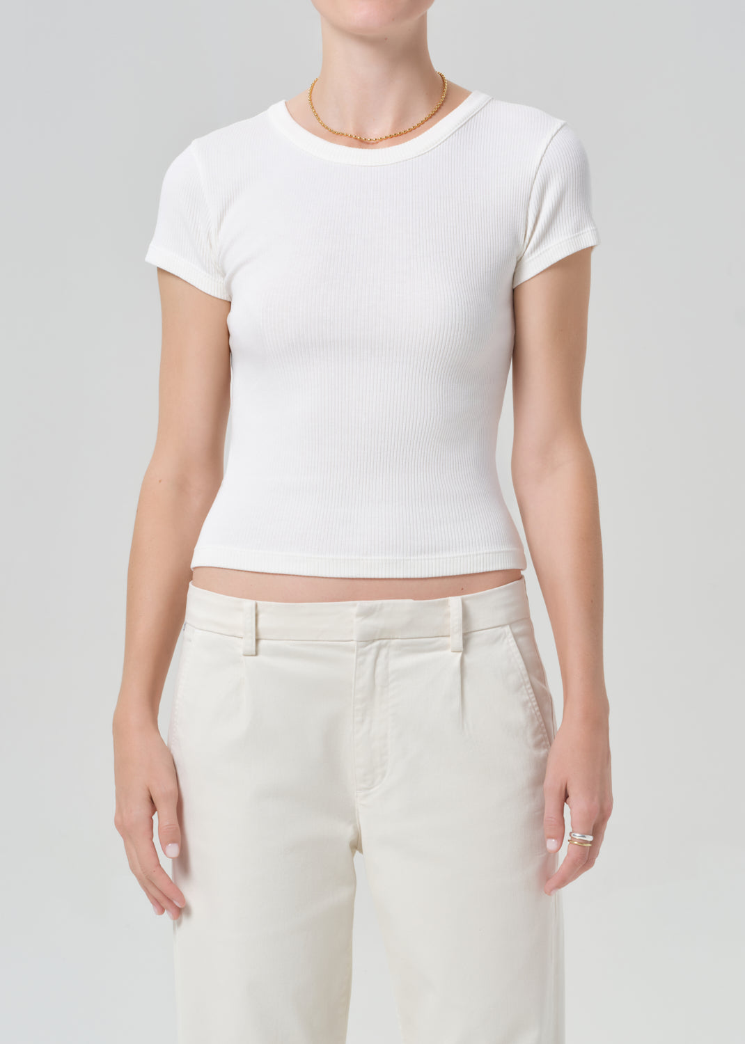 Person wearing a white t-shirt and light-colored pants on a plain background