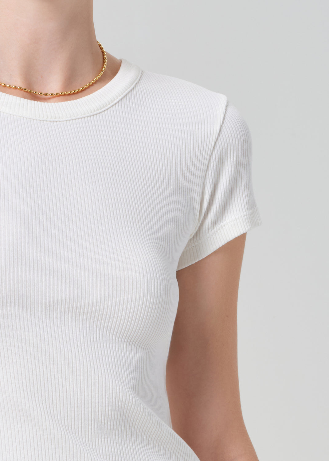 White ribbed knit t-shirt worn by a person on a light gray background