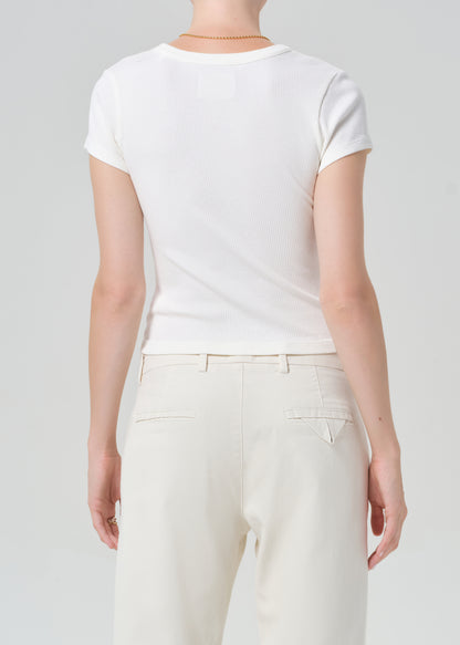 Person wearing a plain white t-shirt and light-colored pants on a neutral background