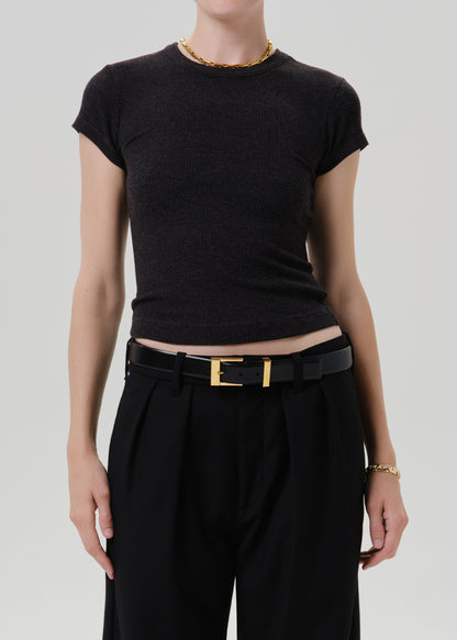 Person wearing a black ribbed cap sleeve tee on a grey background