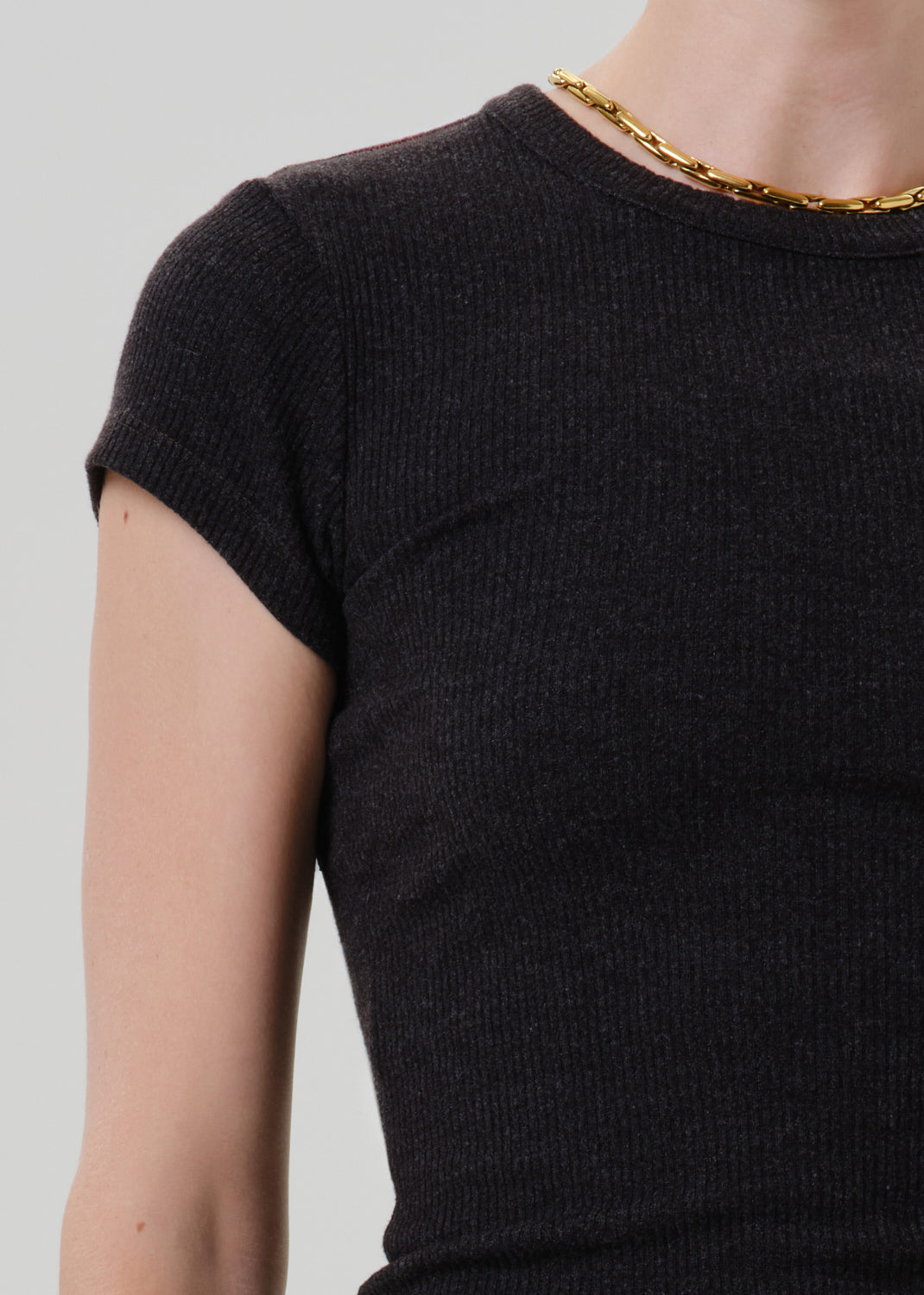 Close-up of a black ribbed cap sleeve tee on a grey background