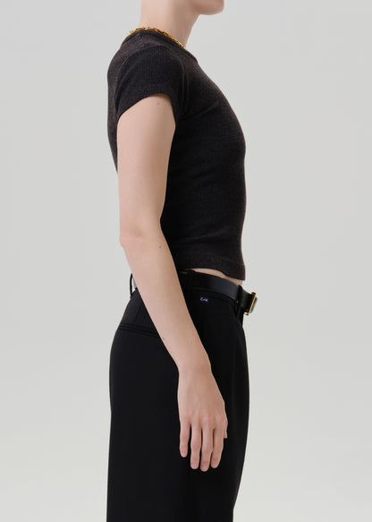 Person wearing a black ribbed cap sleeve tee with black wide leg trousers viewed from the side on a grey background