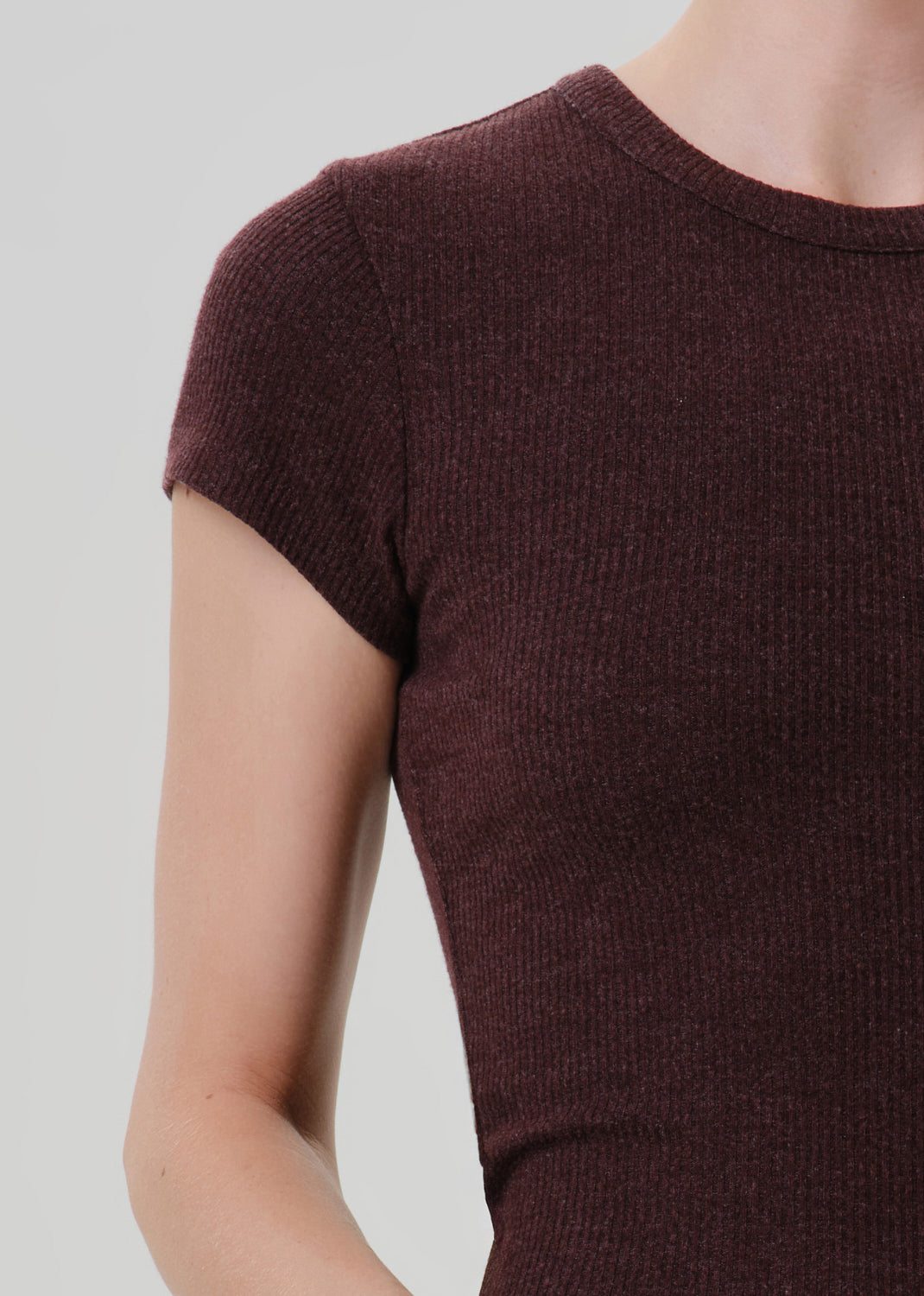 Close-up of a person wearing a short-sleeve ribbed knit top in a deep burgundy or maroon color, shown against a grey background.