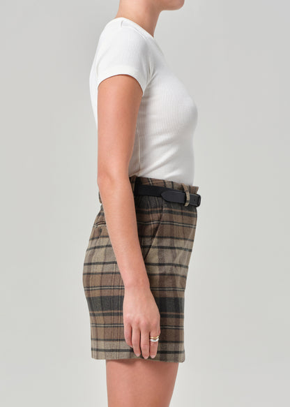 Person wearing a white t-shirt and plaid skirt on a plain background