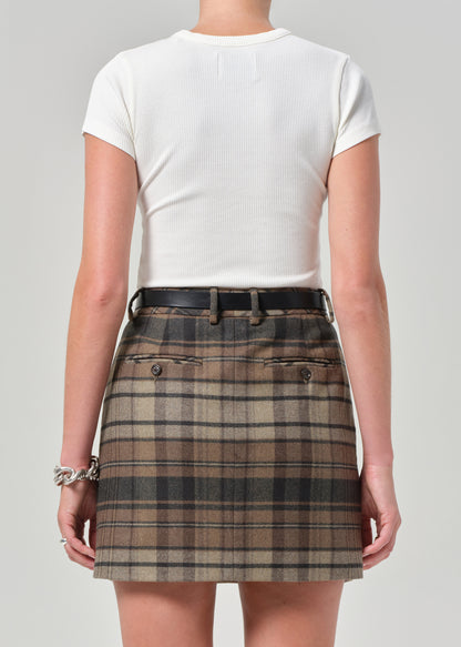 Person wearing a white top and plaid skirt on a plain background