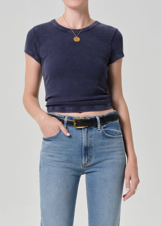 Person wearing a navy blue crop top and blue jeans on a plain background