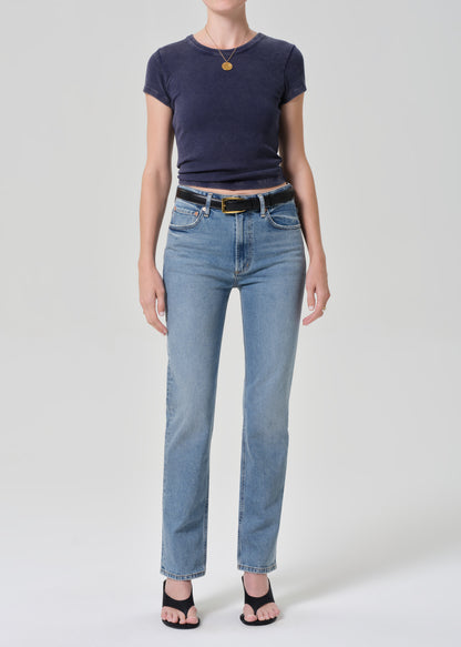 Person wearing a navy t-shirt and light blue jeans on a grey background