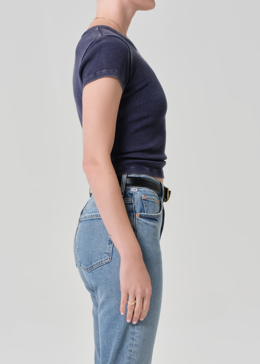 Person wearing a navy t-shirt and blue jeans on a light gray background